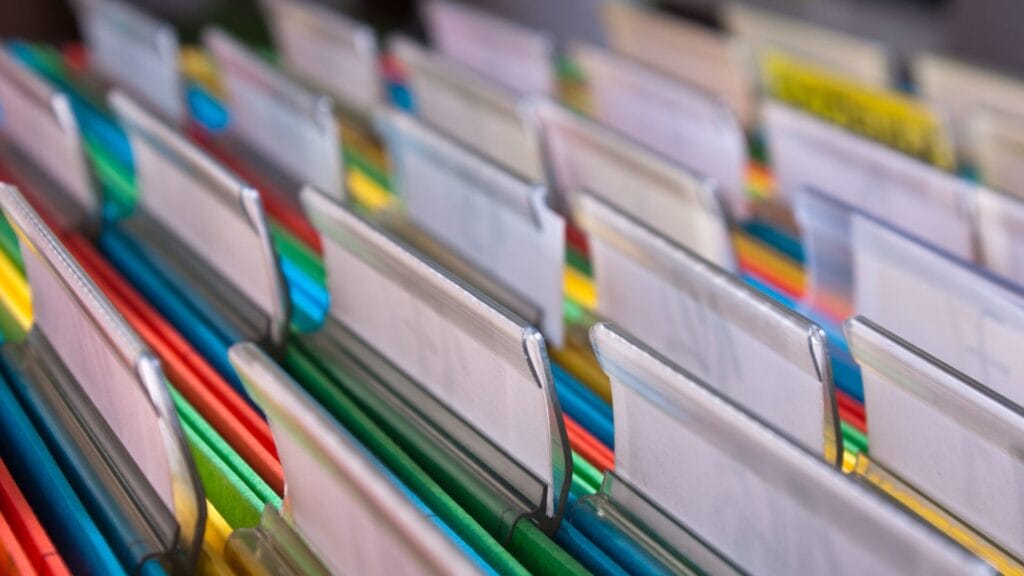 Close-up of color-coded file folders with blank tabs, representing structured documentation and organization for multilingual localization processes.
