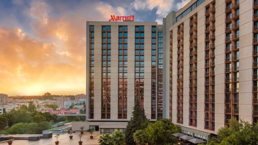 Sunset over the Lisbon Marriott Hotel, a tall modern building with reflective windows and balconies, which hosted the 2025 Game Quality Forum attended by QA, localization, and game development professionals.