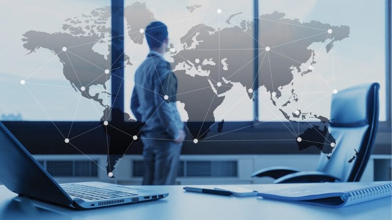 Man standing in front of window showing a world map with data points on