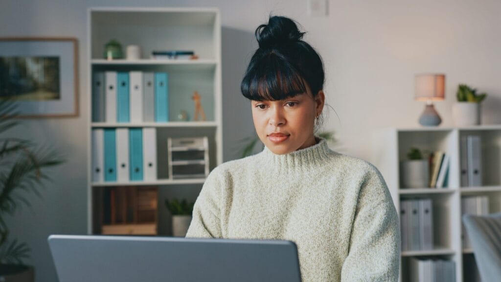 A woman in a light sweater sits in a home office, focused on her laptop, representing a developer or content manager working on WordPress localization tasks in a calm, professional environment.