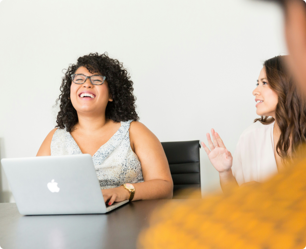 Zwei Frauen schauen lachend auf einen Laptop